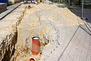 Replacement of communications on city street, vertical end of orange plastic pipe in sand trench