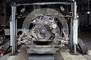 Replacement used engine on a table mounted under raised car on lift  for installation after a breakdown and repair in a vehicle