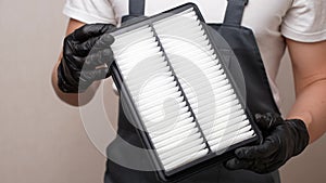 Replacing air filter in car. Car mechanic holds car air filter in his hands in black gloves, close-up. Concept of timely