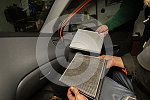 Replacing the air filter in the car interior A man holds in his hands an old and a new air filter from the inside of a