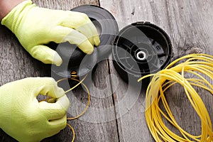 Replacing  line in the head of the grass trimmer, hands in gloves