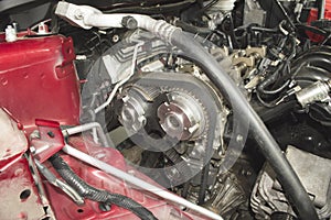 Replacing the timing belt on a red car in a car repair shop