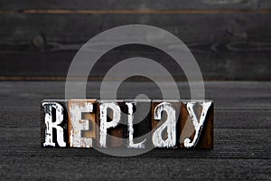 Replay. Text on a dark textured wooden background
