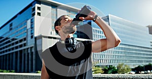 Replenished and recharged for the next round. a young man drinking water during his workout in the city.