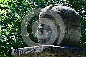 Replica of Olmec round stone head statue on pedestal