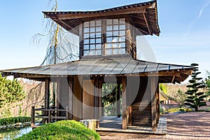 Replica of small wooden Japanese temple next to stream against blue sky