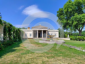 Replica of traditional Roman house with fountain and green nicely cut grass