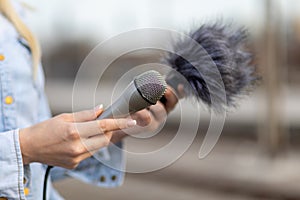 Reporter on the spot, holding microphone and dictaphone sound recorder in hand