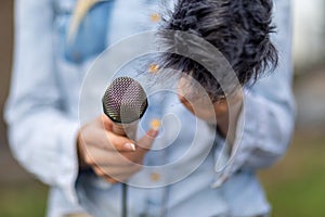 Reporter on the spot, holding microphone and dictaphone sound recorder in hand