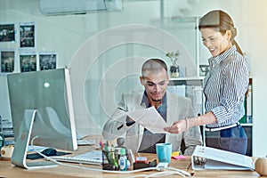 These reports are looking good. two businesspeople looking through some paperwork in an office.