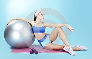 Repose. Sportswoman with Sport Equipment - a Fitness Ball and Dumbbells photo