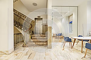 Representative marble and gold metal staircase in an office with glass partitions and wooden furniture