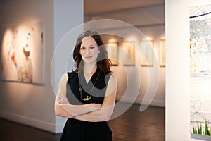 Representing the artists. A portrait of a young woman standing in front of numerous paintings hanging on the walls of a