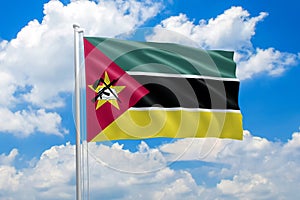 Mozambique national flag waving in the wind on clouds sky. High quality fabric. International relations concept photo