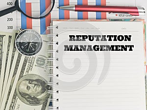 REPUTATION MANAGEMENT written on note book with pen,eye glasses,compass,money and chart.