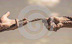 Rescue, help, helping gesture or hands. Conflict tug war. Rope, cord. Hand holding a rope, climbing rope, strength and