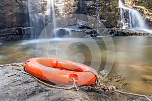 Rescue lifebuoy on the rock with nature waterfall background.