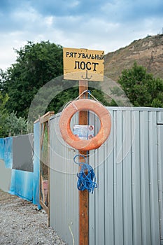 Rescue station on beach on sunny day. sign on the shore. Text in Ukrainian: rescue post. Red life preserver