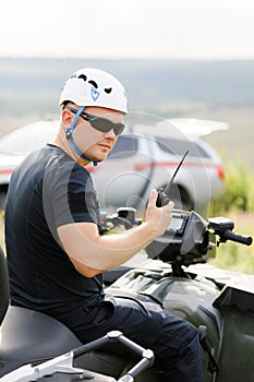 The rescuer, a beautiful athletic physique, rides an ATV in the middle of the field