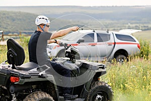 The rescuer, a beautiful athletic physique, rides an ATV in the middle of the field