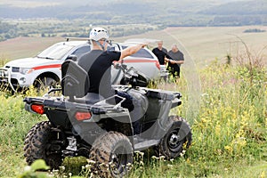 The rescuer, a beautiful athletic physique, rides an ATV in the middle of the field