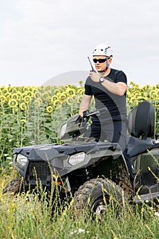 The rescuer, a beautiful athletic physique, rides an ATV in the middle of the field