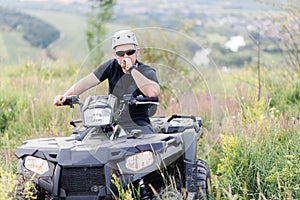 The rescuer, a beautiful athletic physique, rides an ATV in the middle of the field