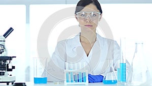 Reseach scientist sitting in laboratory looking at camera