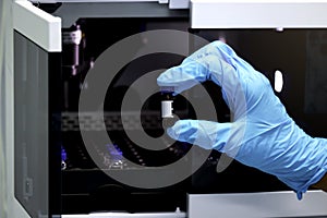 Research scientist hand with blue chemical protective gloves holding vial small bottle for doing experiment. Chemist working in