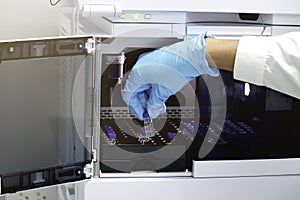 Research scientist hand with gloves holding vial small bottle to put tray inside injection section of High Performance Liquid