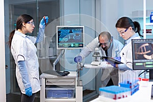 Research scientists working on monitor with medical equipment analyzing blood, genetic material samples