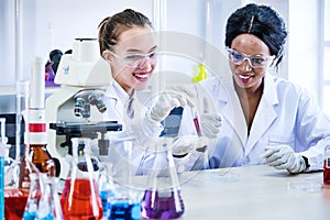 Research teams Cacausian and African female, Two  scientist in protective glasses looking and testing tube chemical in laboratory