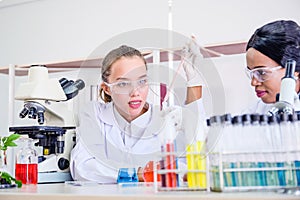 Research teams Cacausian and African female, Two  scientist in protective glasses looking and testing tube chemical in laboratory