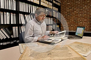 Researcher in Archive Examining Maps and Other Archival Material