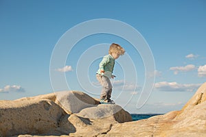Researcher. Big adventures of a little boy. Baby child on white stones near the sea.