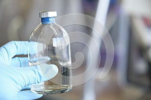 Researcher hand wearing gloves holding a bottle for anaerobic cultures, with cap and septum