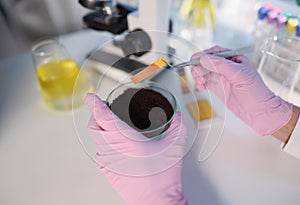 Researcher hold small glass flask with soil, performing ph test strip