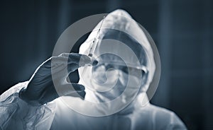 Researcher in protective suit preparing a syringe