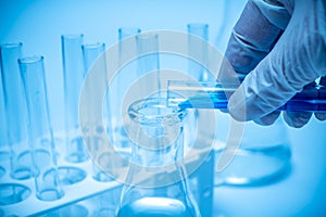 A researcher`s hand holding a test tube containing blue liquid