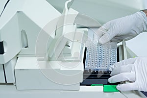 Researcher or scientific introducing a 96 wells plate in quantitative PCR machine