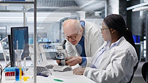 Researcher using microscope and specimen tray in laboratory workspace