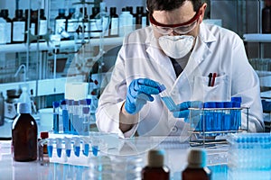 Researcher working with sample of blue fluid in tube for analysis in the science lab