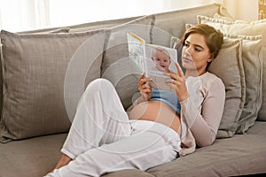 Researching the A to Zs of pregnancy, childbirth and parenting. Shot of a young pregnant woman reading a baby book at