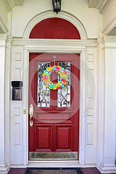 Resentails red front door with leaded glass in white house colorful Day of the Dead Halloween wreath