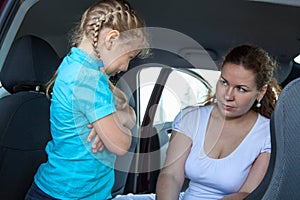 Resentful child refusing get in safety seat under mother severe look photo