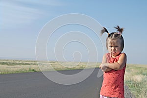 Resentful child is standing and don`t want to go anywhere defend own position . Little girl in kazakh steppe