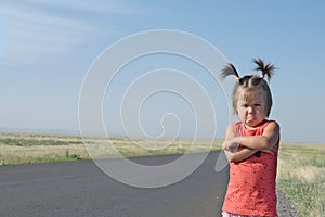 Resentful child is standing and don`t want to go anywhere defend own position . Little girl in kazakh steppe