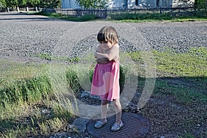 Resentful child is standing and don`t want to go anywhere defend own position Little girl in pink sundress at summer photo