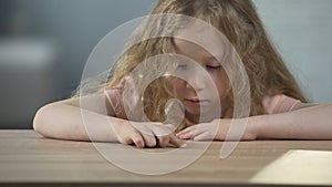 Resentful long-haired girl sitting at the table and thinking about own behaviour