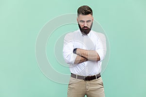 Resentful man, with arms folded, over light green background in studio shot